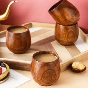 Tasse à thé en bois de style japonais vintage, posée à côté d'une théière dorée élégante sur fond rose