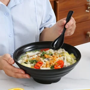 personne qui déguste des ramens dans un bol à ramen japonais de couleur noir avec cuillère