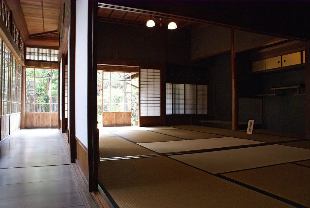 Salle traditionnelle japonaise avec tatamis et portes coulissantes shoji, incarnant l'esthétique minimaliste et naturelle du Japon.